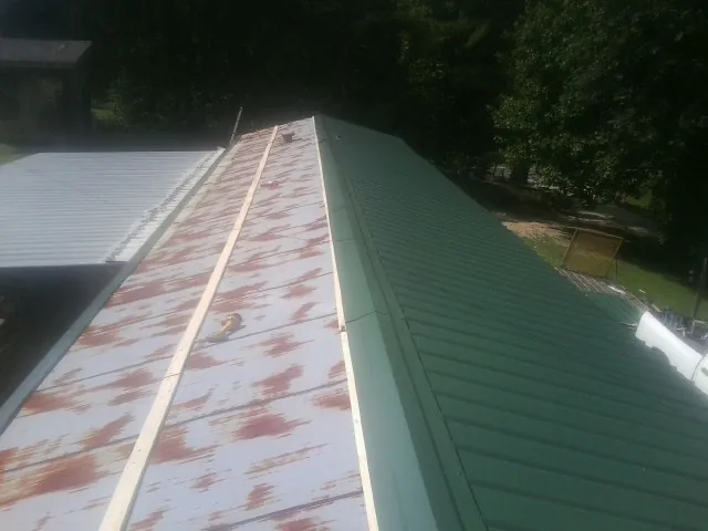 Old rusted panels beside newly installed green metal roofing — Wind Damage Roof Repair by Roofing Brothers in Sanger