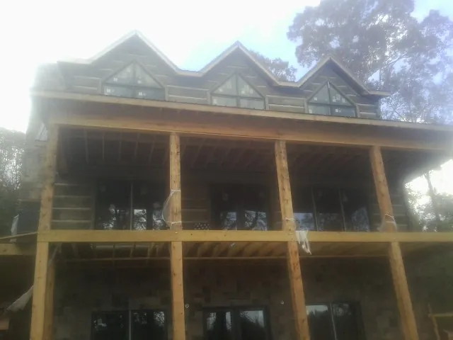 Dormers and porch framing on a large log home under construction — Roof Coating work by our crew in Sanger